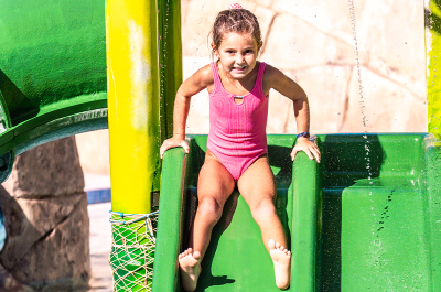 Niña disfrutando de un tobogán acuático en Aquamijas, una escena perfecta para inspirar ideas para comuniones originales al aire libre.