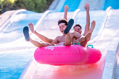 Dos jóvenes disfrutando de un tobogán acuático en Aquamijas durante el aniversario corporativo del parque, celebrando 40 años de diversión y experiencias inolvidables bajo el sol.