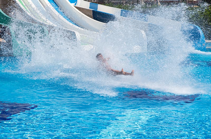 Persona deslizándose por un tobogán acuático en un parque de Málaga, salpicando agua y disfrutando de un plan de ocio ideal para el puente de mayo 2026.