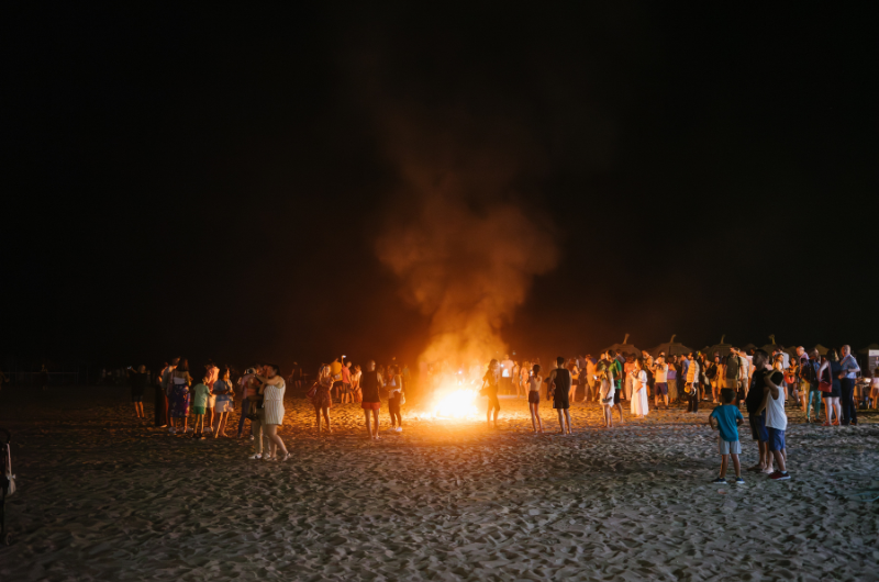Personas reunidas alrededor de una hoguera en la playa durante la celebración de San Juan Málaga 2026, disfrutando de una de las tradiciones más populares de la noche de San Juan en la Costa del Sol.
